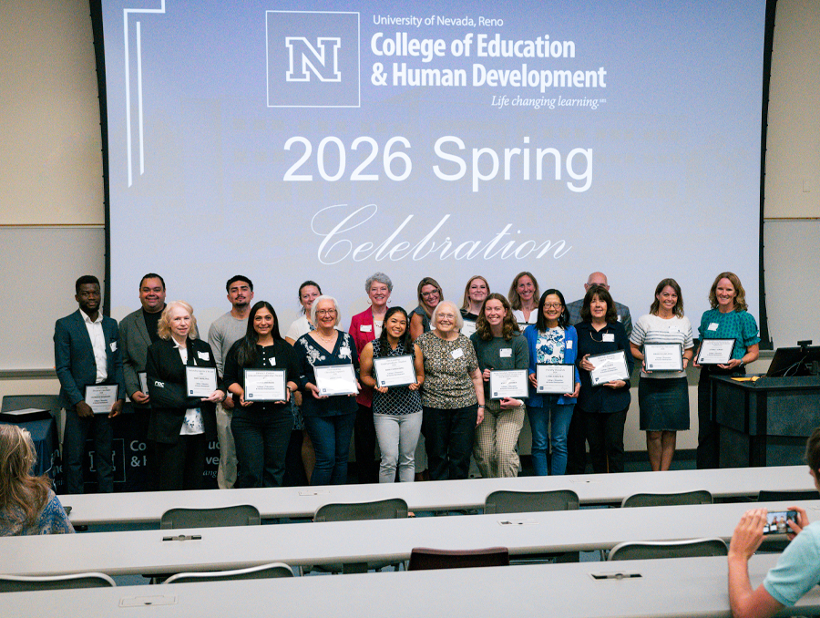Award winners gather for a photo at the front of an auditorium.
