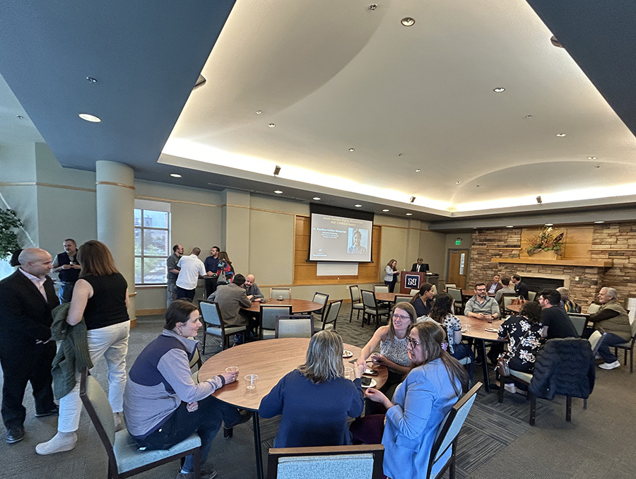 A group of people are gathered in a conference room with round tables.