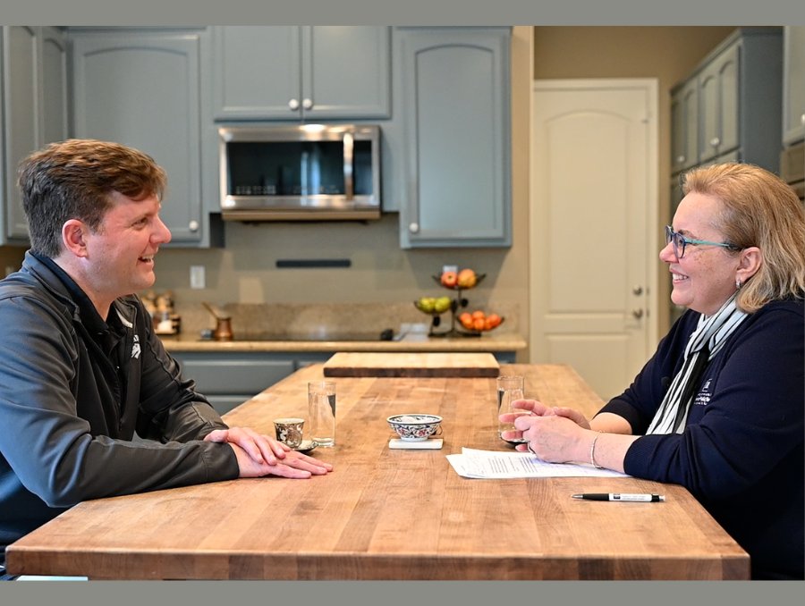 Matt Strickland and Dean Muge Akpinar-Elci talking at a kitchen table.