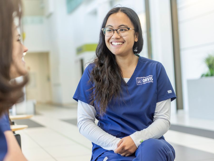 Nursing student smiling in scrubs.