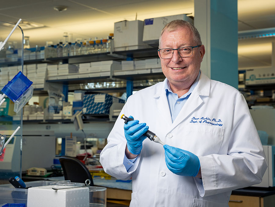 Dean Burkin in his lab holding a syringe.