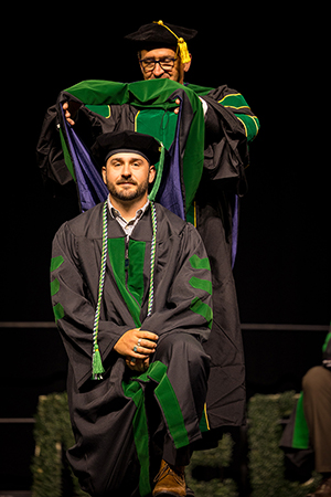 Cameron Shonnard, M.D., hooded by Paul Shonnard, M.D. at the 2026 Commencement Ceremony.