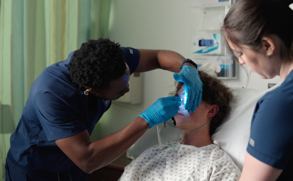 Luka working with a patient in a hospital setting, while a doctor observes.