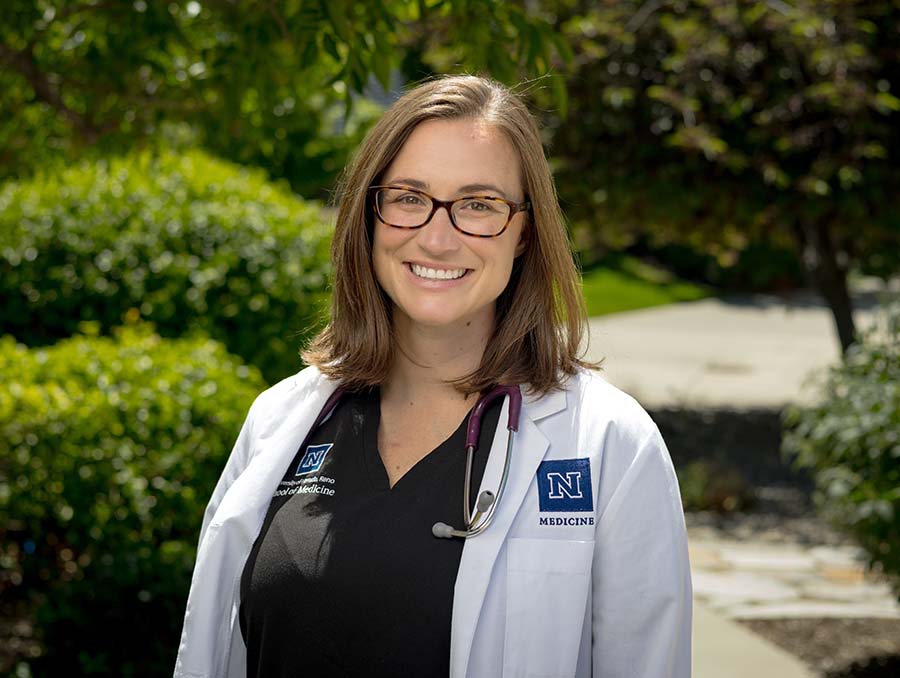 Miranda Hellman wearing a white coat and stethoscope outdoors. 