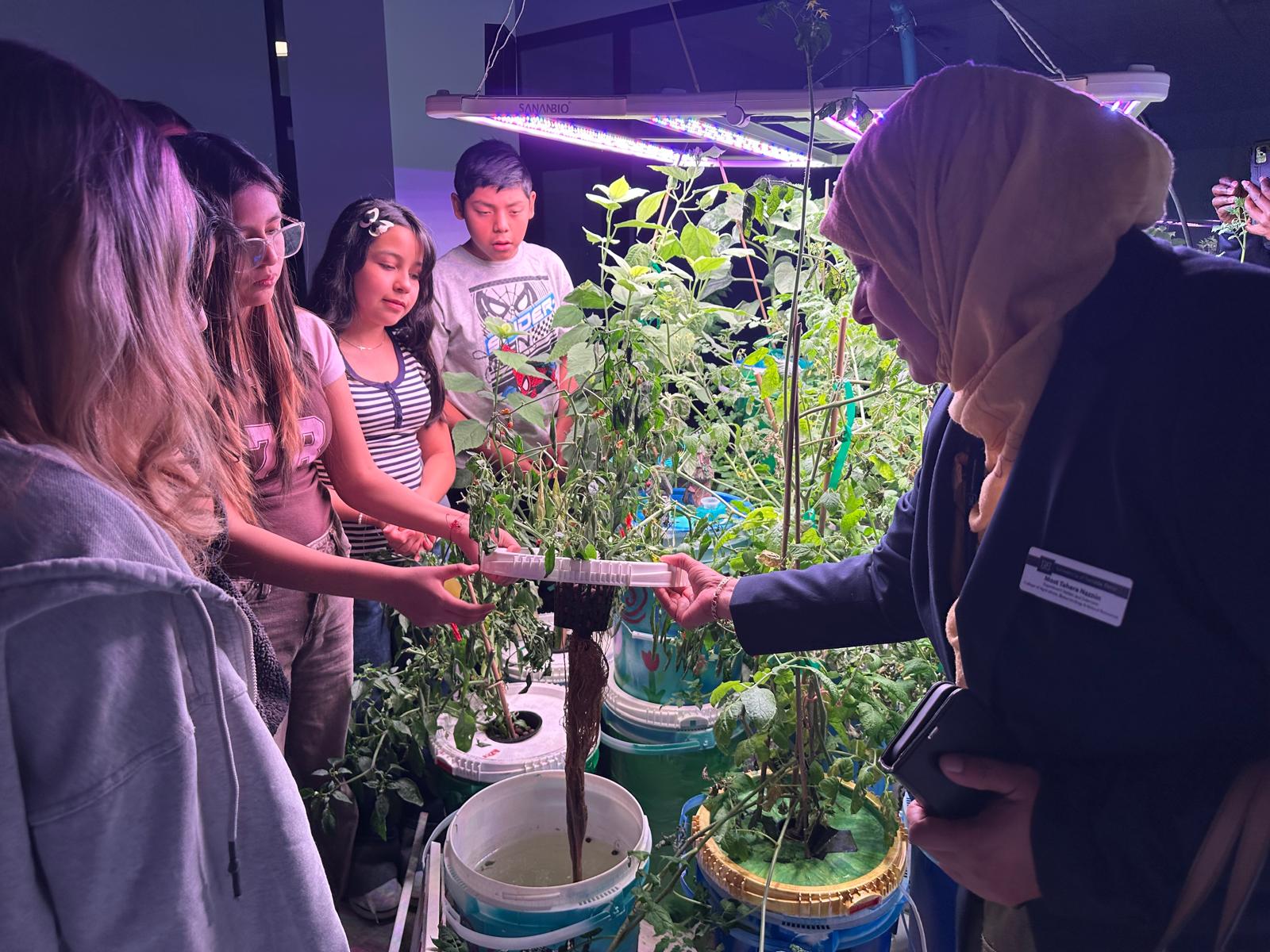 Most Tahera Naznin listens as students from WYLEES Middle School explain how their hydroponic garden operates.