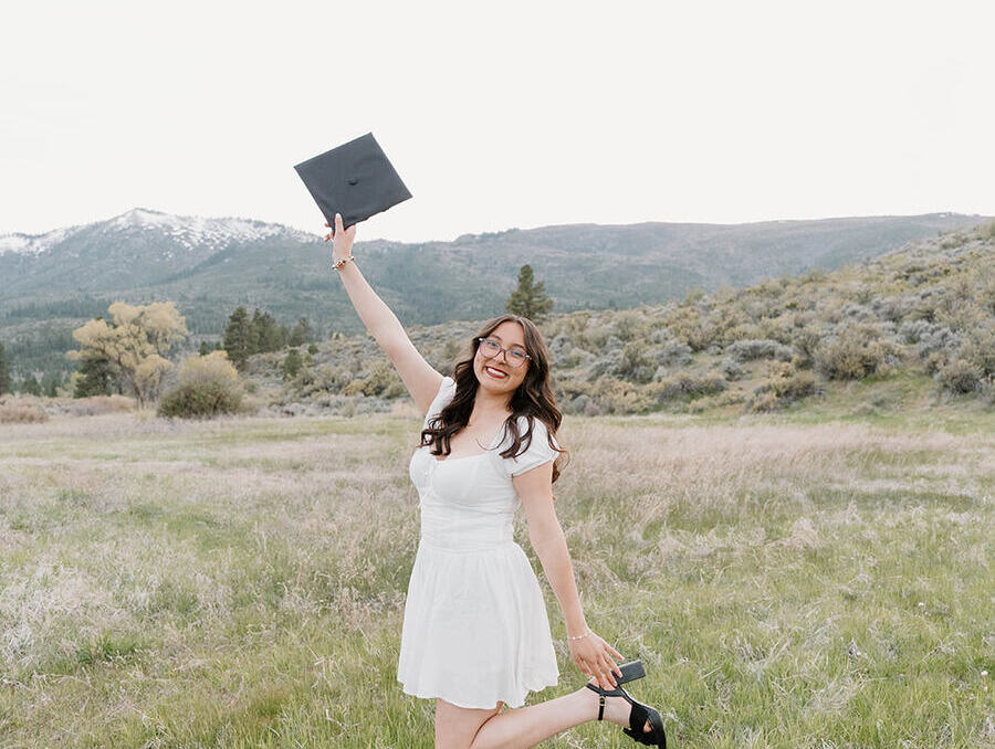 graduate poses near mountains