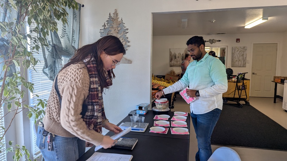 Amanda and Mohit setting a table with food bowls and recipes. 