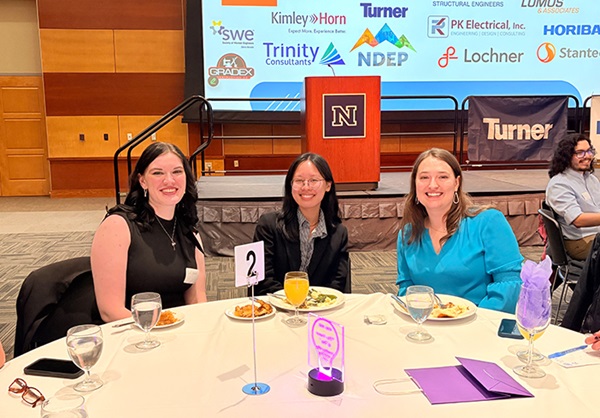Three young women sit at a banquet table.