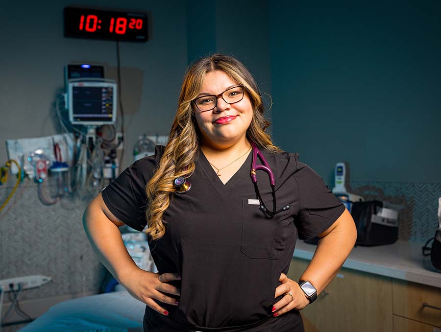 Zoee Castro wearing scrubs and a stethoscope in an emergency clinical room. 