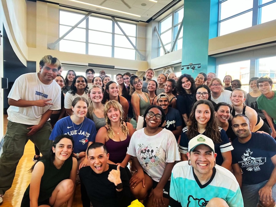 A large group of people in a fitness room, smiling together, posing for the photo.