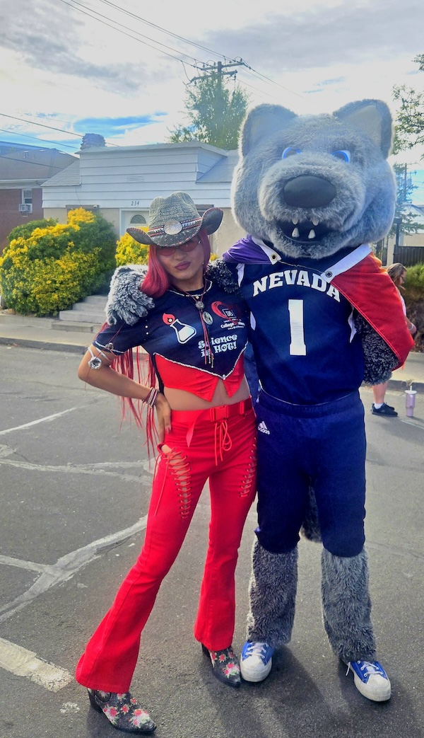 La Chonta smiles at the Reno Pride Festival, posing with Alphie, the Mascot of the University of Nevada, Reno.