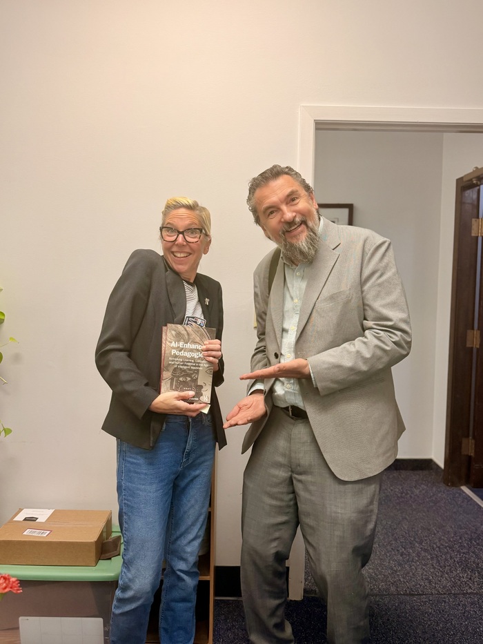 Two people holding a book and smiling.