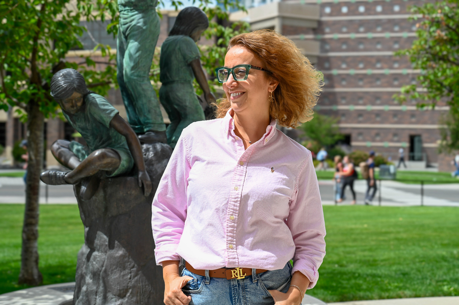 Gokce stands in front of statue on campus.