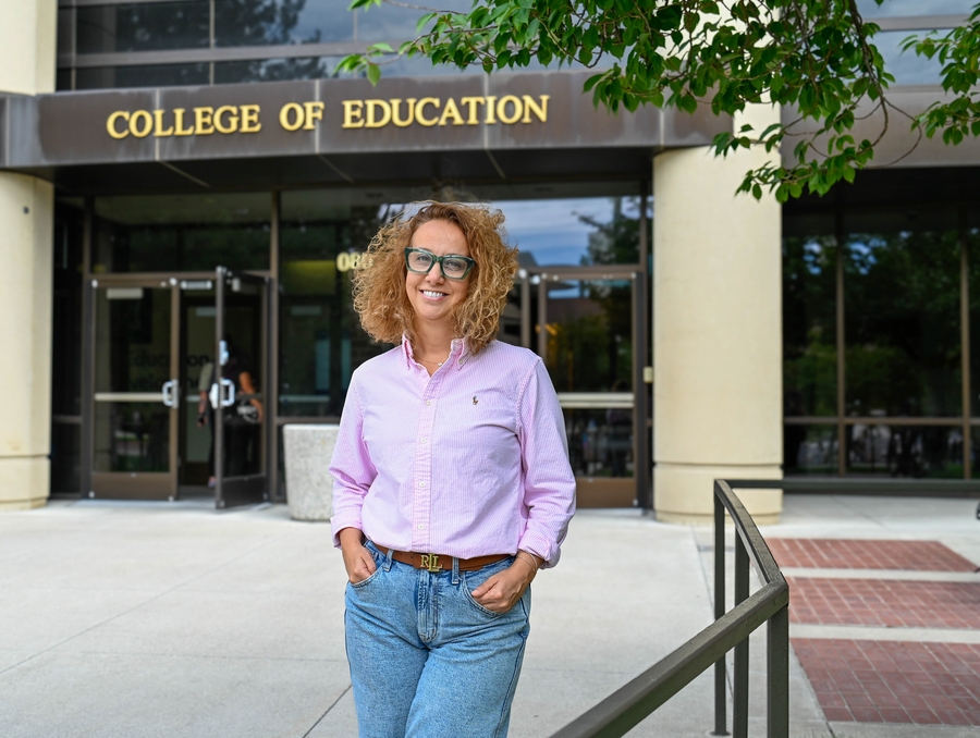 A woman stands in front of the College of Education building. 