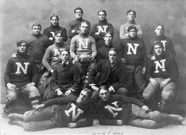 The Nevada men's football team from 1903 posing together wearing sweaters with an N on them.