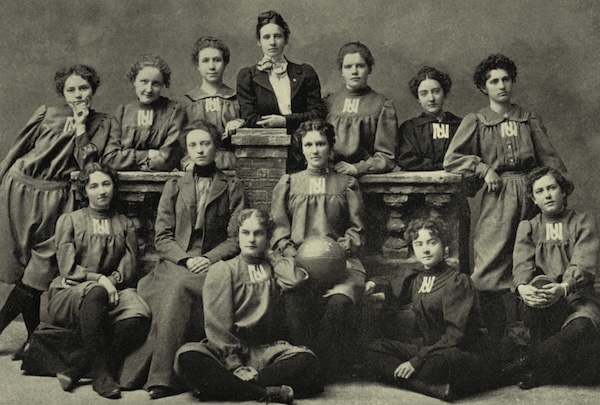 The Nevada Women's basketball team poses in uniforms with an interlocked UN on a court.