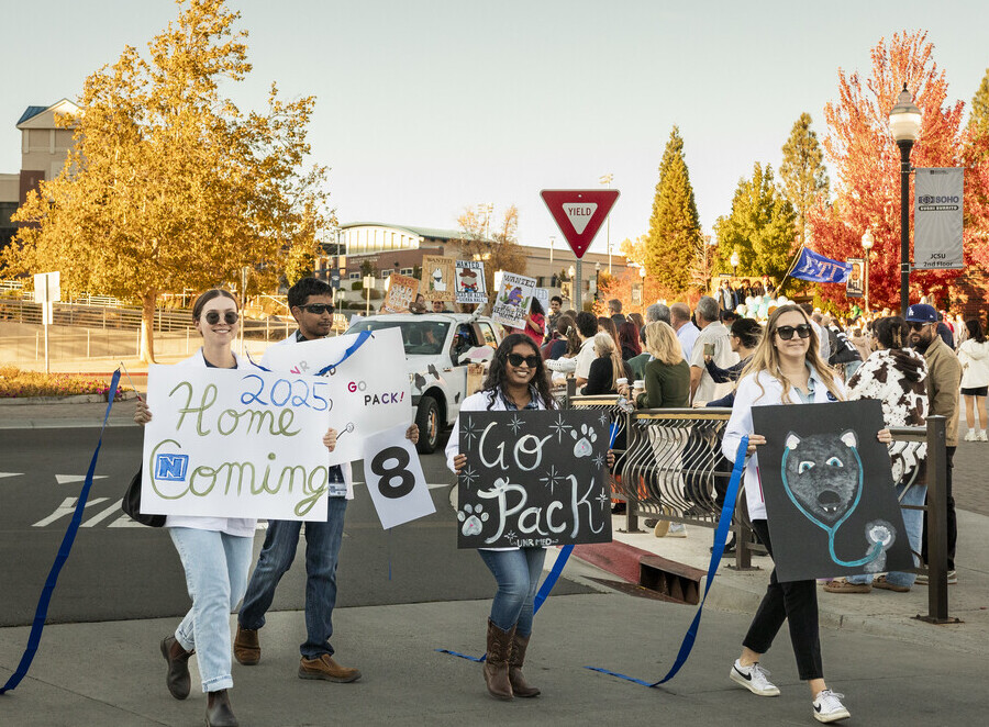Students hold signs and march in a homecoming parade.