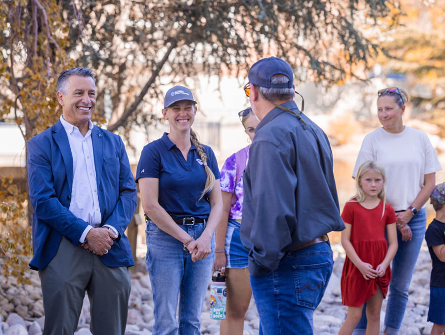A gropu including President Sandoval laugh as Crookshanks gives context about the fish.