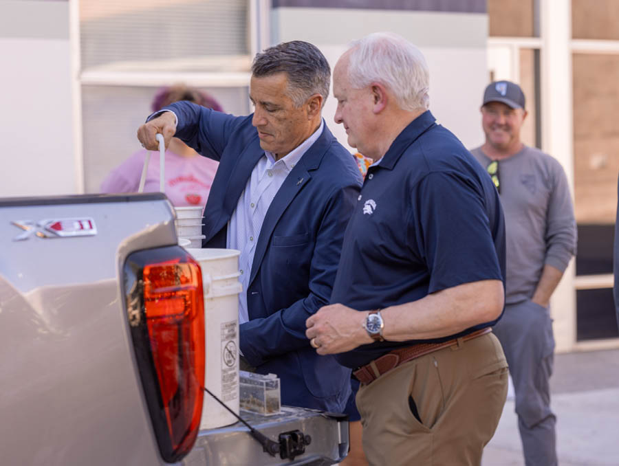 President Sandoval and Provost Thompson grabbing buckets full of fish to bring to the lake.