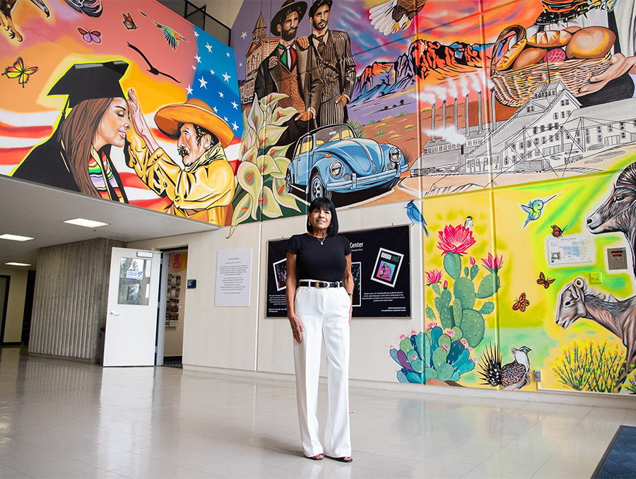 Mary Avalos poses in front of a colorful mural.