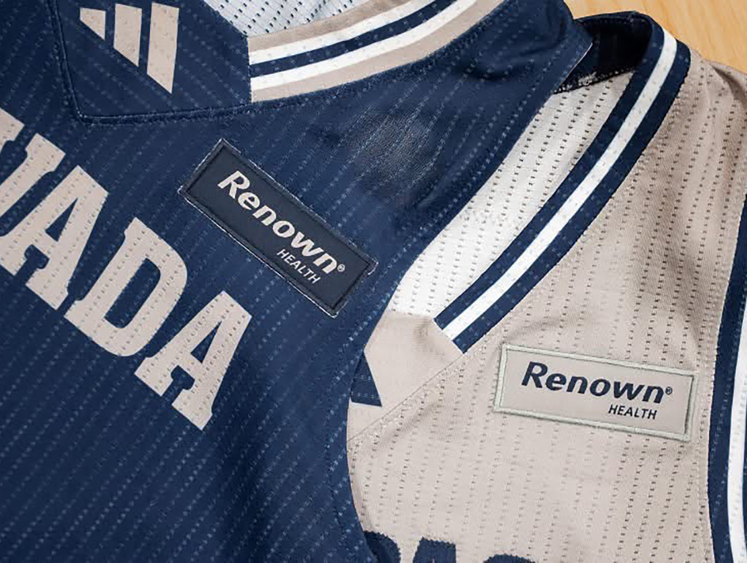Two jerseys, one dark and one light, with a rectangular patch with text RENOWN on the left shoulder area