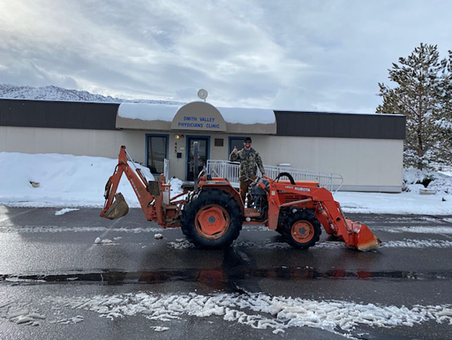 Kaleb Wartgow, M.D., on a tractor shoveling snow outside the clinic.