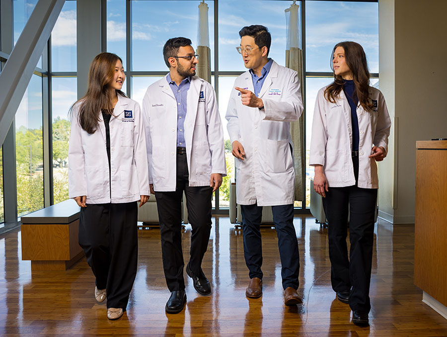 Eric Kim, M.D., walking and talking with three medical students.