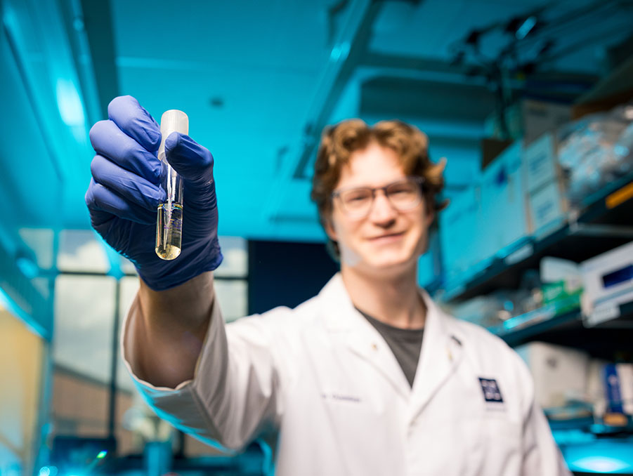 Ryan Gustafson holding a test tube in front of himself.