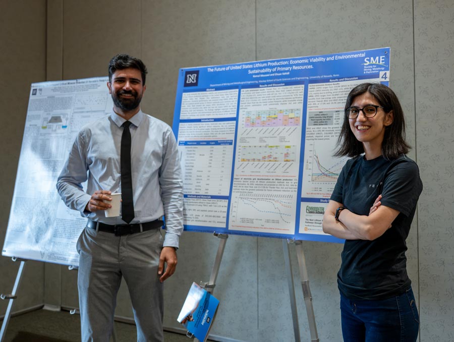 Two people smile and stand near an academic poster.