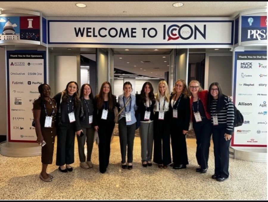Students in business attire stand smiling for a photo at the PRSSA ICON conference.