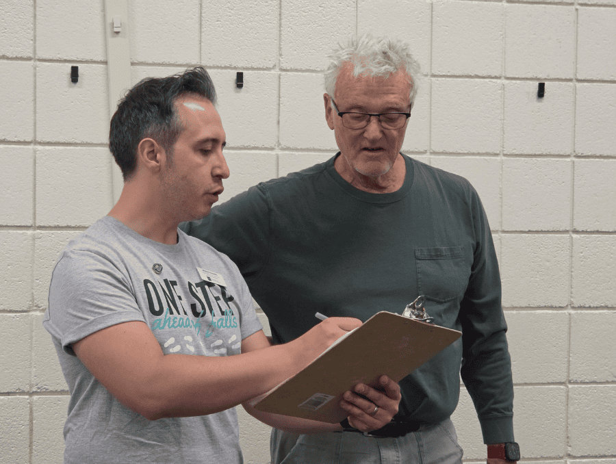Two men are looking at a clipboard together.
