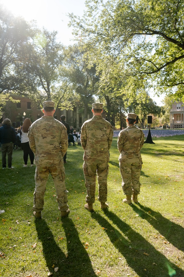 Three service members in uniform watch the ceremony, remembering 9/11.