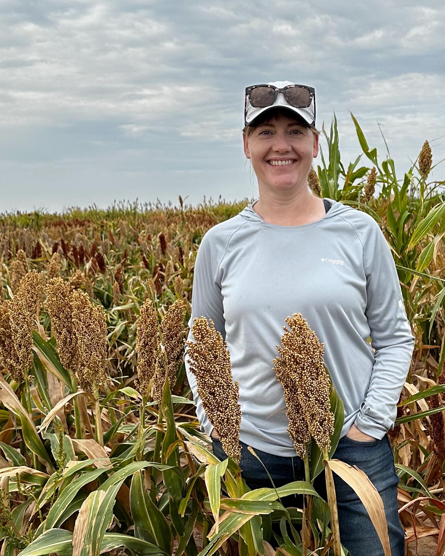 Melinda Yerka posing in a field of growing sorghum. 