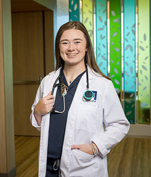 Bailey ivory in a white coat standing in a hallway.