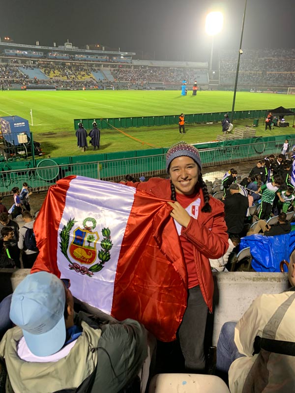 Alejandra poses with a flag at a soccer game.
