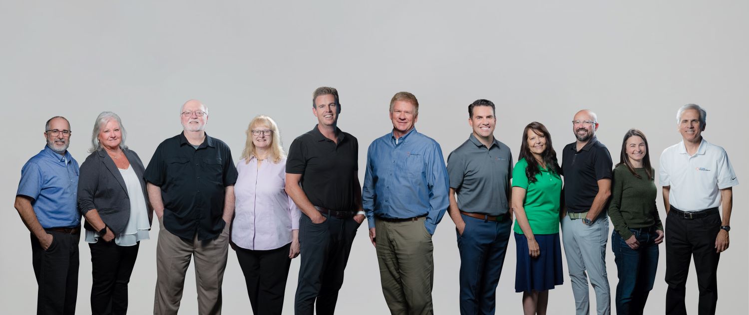 A large group of men and women in professional clothes on a white background, smiling.