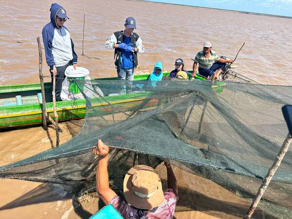 A group of people in muddy water holding a large fishing net