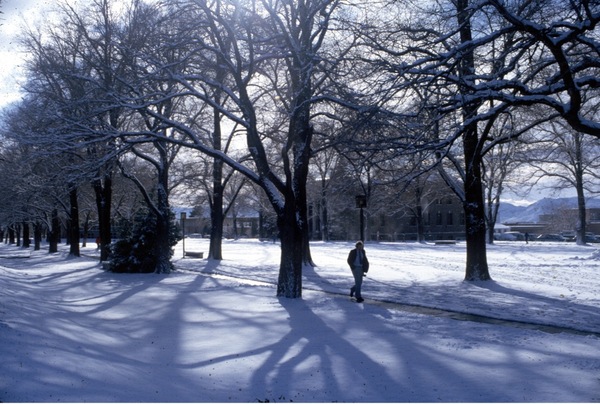 The University's quad covered in snow with a single person walking along the path and footprints visible in the snow.