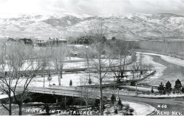 A historical image in black and white showing the Truckee River in downtown Reno from around 1910. Caption on image: Winter on the Truckee, #50 Reno, Nev.