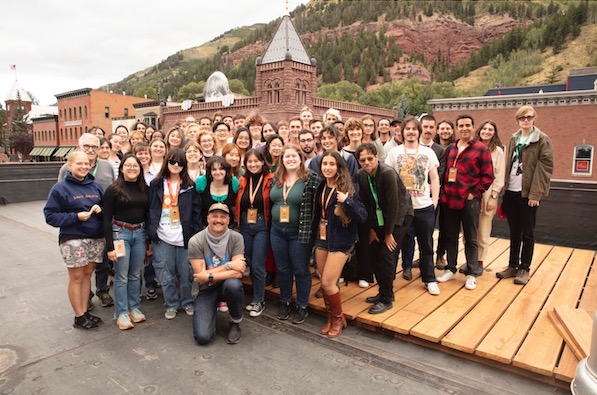 A group of about 50 people pose for a group photo in Telluride wearing name badges.