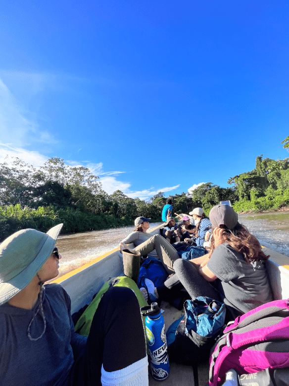 A group of individuals in a long canoe floating along a river.