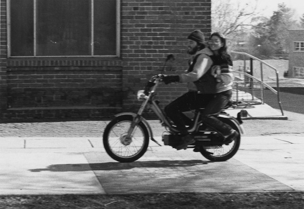 Two students riding a moped on campus.