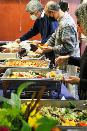 Faculty and staff wearing masks and helping themselves to the buffet line of food