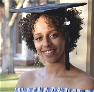 Shot of Elda Solomon wearing her mortarboard near the Quad