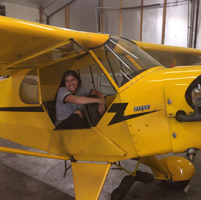 Alejandra Griswold in a small yellow airplane.