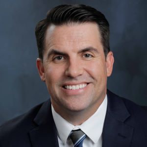 Tom Simpkins headshot, smiling in a suit.