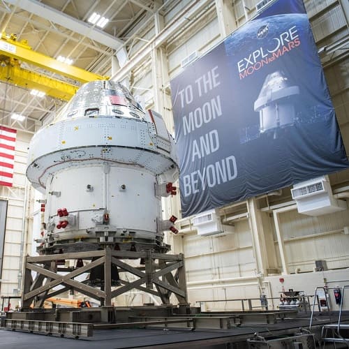 The Artemis spacecraft in a NASA hangar with a big sign that reads "To the moon and beyond" next to it