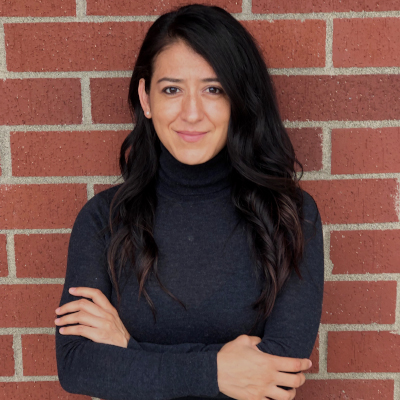 Ruby Batz smiling with a brick wall background.