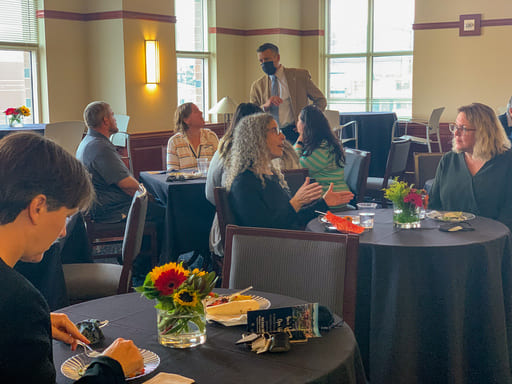 Faculty and staff socializing with each other and President Brian Sandoval while eating at tables