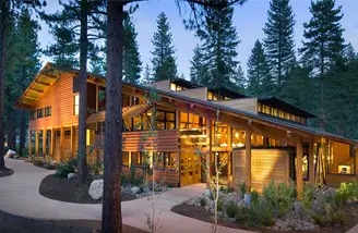 Evening falls around the Prim Library at the University of Nevada, Reno at Lake Tahoe, a wooden building with a slanted roof that sits among the trees.
